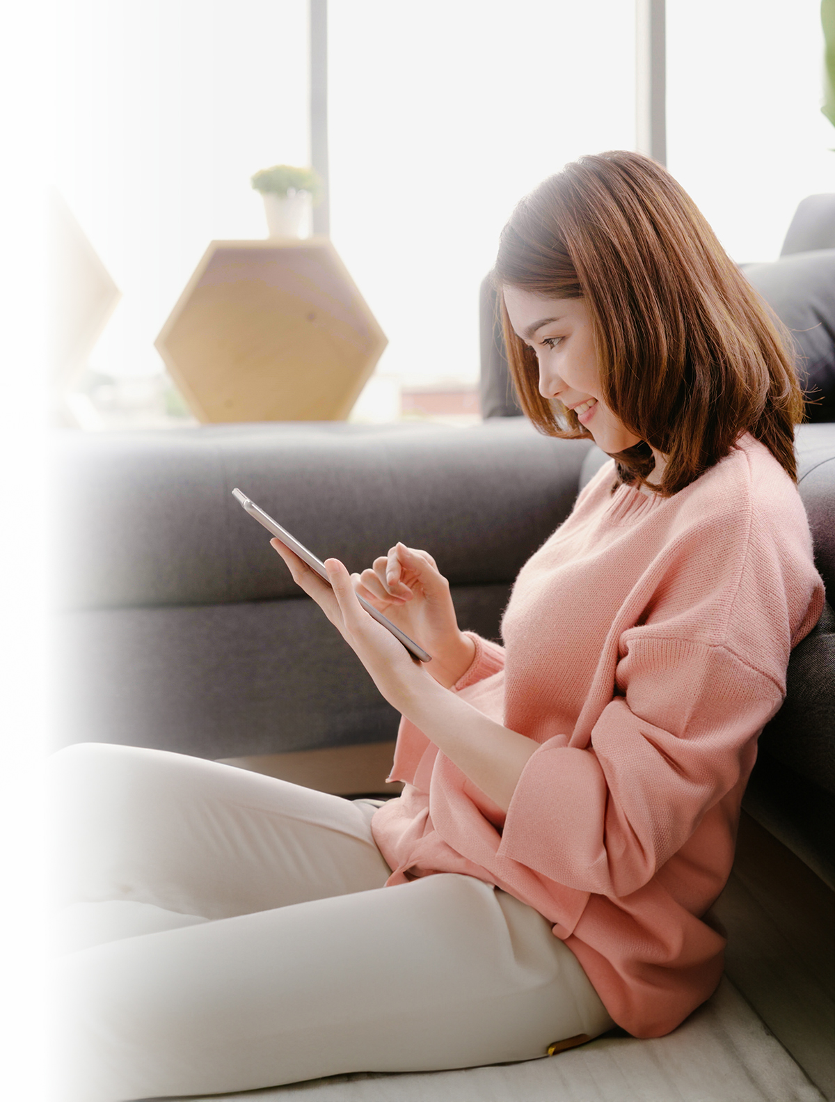 Asian woman using tablet while lying on home sofa in her living